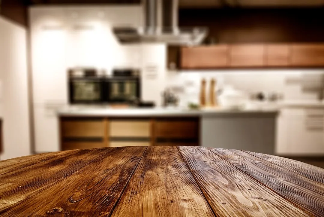 Holztisch im Hintergrund mit freiem Platz für Ihre Dekoration und unscharfem Küchenhintergrund.